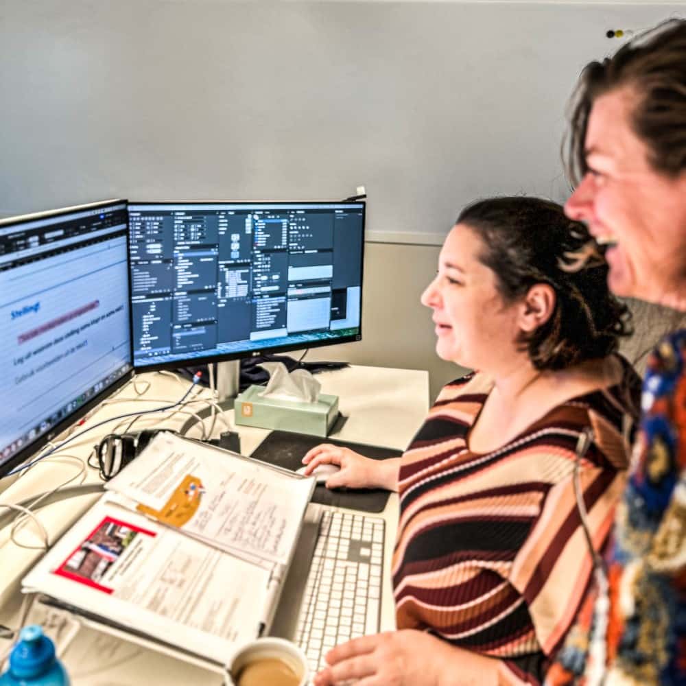 Two Crius Group editors working through a manuscript beside the marked-up text on screen